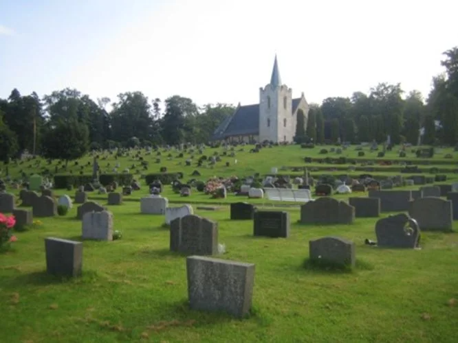 Kirkegården med Borgestad kirke i bakgrunnen. Kirkegården er fylt med gravstener. Foto.