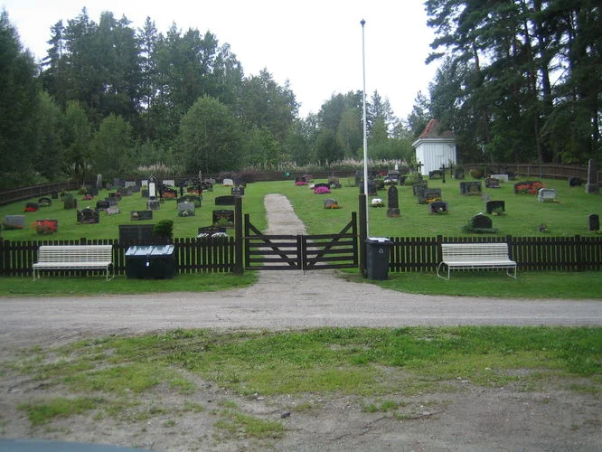 Valebø kirkegård. Veien går forbi, porten med benk på hver side og gjerdet rundt. Foto.